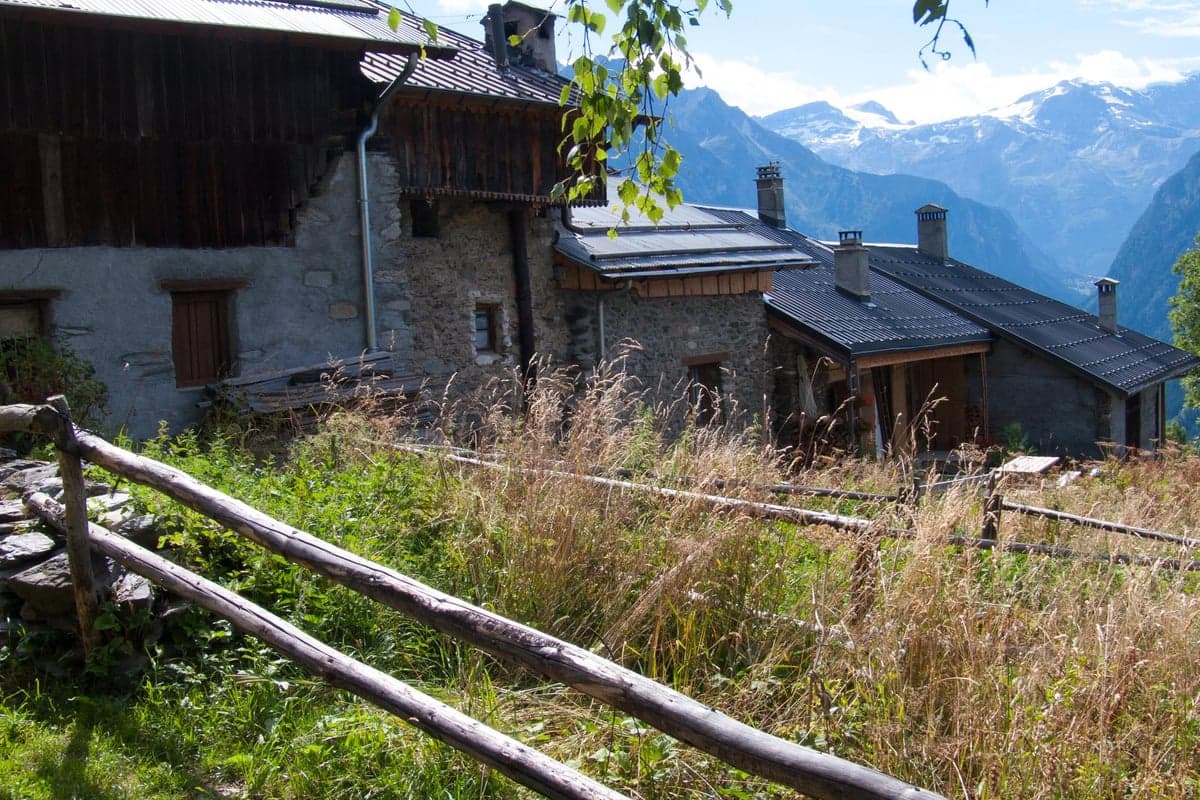 Traditionelle Steinhäuser eines alpinen Bergdorfs mit Bergpanorama im Hintergrund